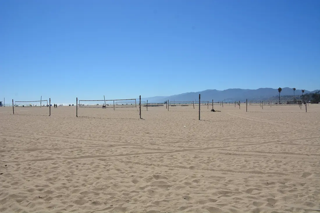 Mehrere Beachvolleyballfelder nebeneinander im Sand, Netze in einer Reihe gespannt