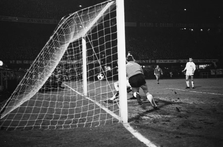 Archivische Schwarzweißaufnahme aus dem Torraum: Ball im Netz, Torlinie und Beine mehrerer Feldspieler