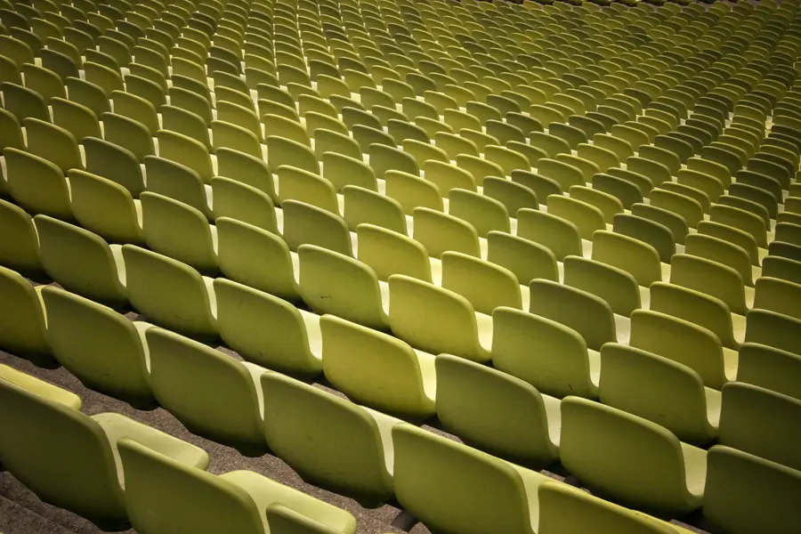 Dicht gestaffelte gelbe Sitzreihen einer Stadiontribüne